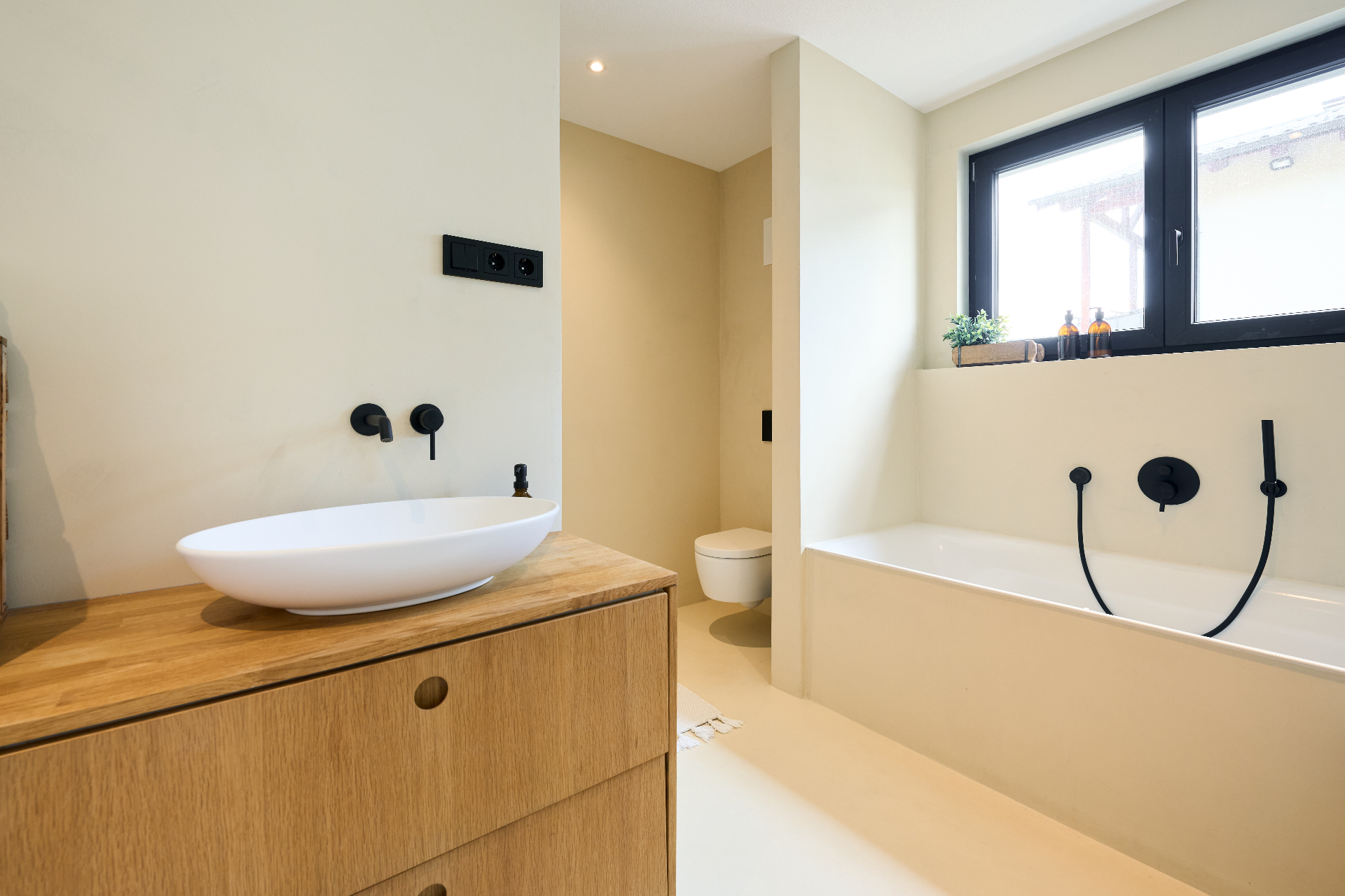 Badezimmer mit Holz-Waschtisch und schwarzen Armaturen